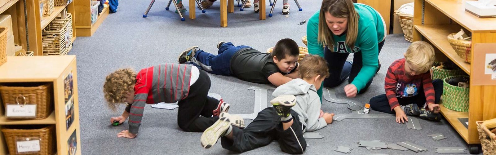 Boys and children centre staff put train tracks together on the floor